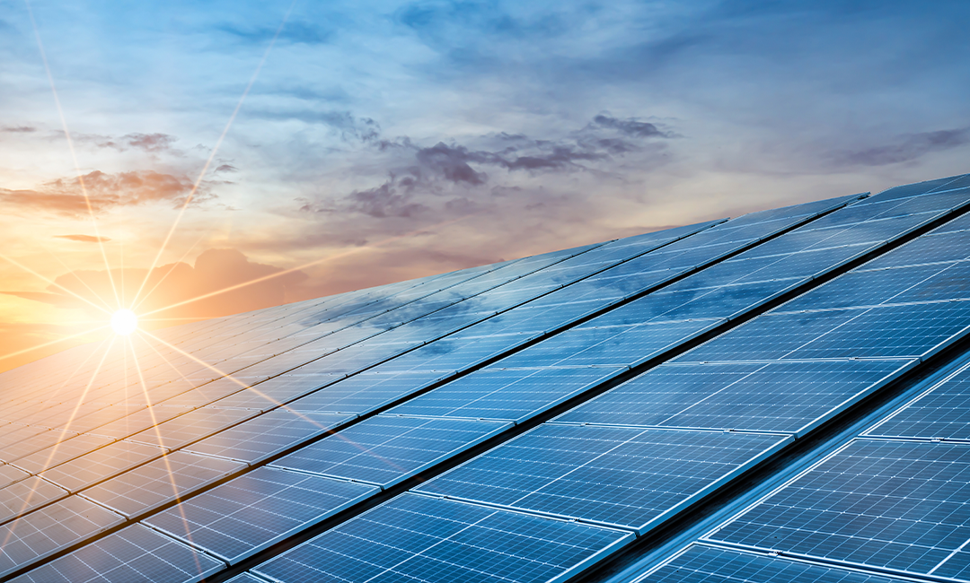 Solar panels reflecting sunlight during a bright sunset.